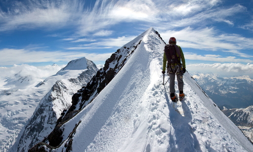 Will Sim on the summit ridge of the Eiger after topping out in to the sunshine from the North Face. On the left the Bernese Oberland stretches as far as the eye can see.